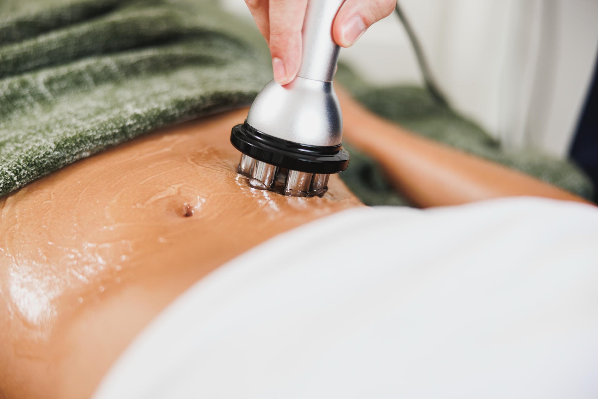 Radio frequency body treatment on a woman's stomach with a multipolar handpiece to firm skin.