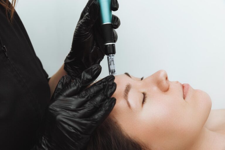 Aesthetician microneedling a woman's forehead with a Dr. Pen during a RegimA microneedling facial.